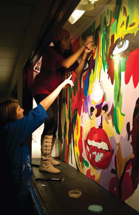 two girls painting art on wall