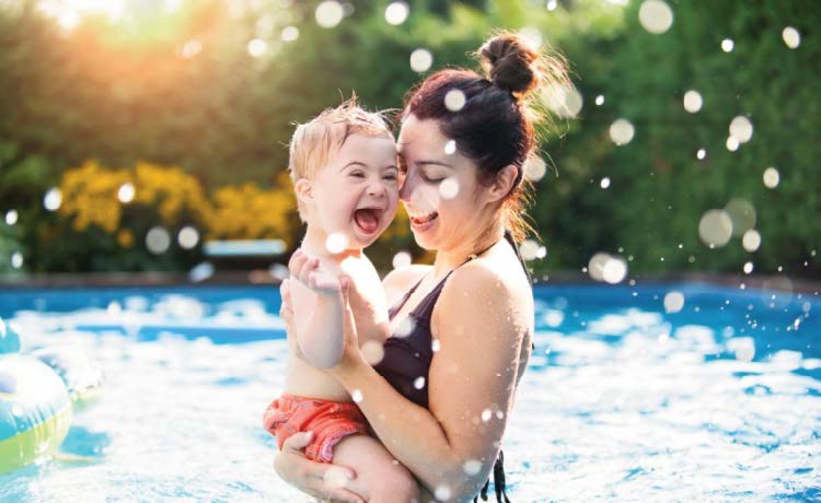 WOMAN HOLDING CHILD IN SWIMMING POOL