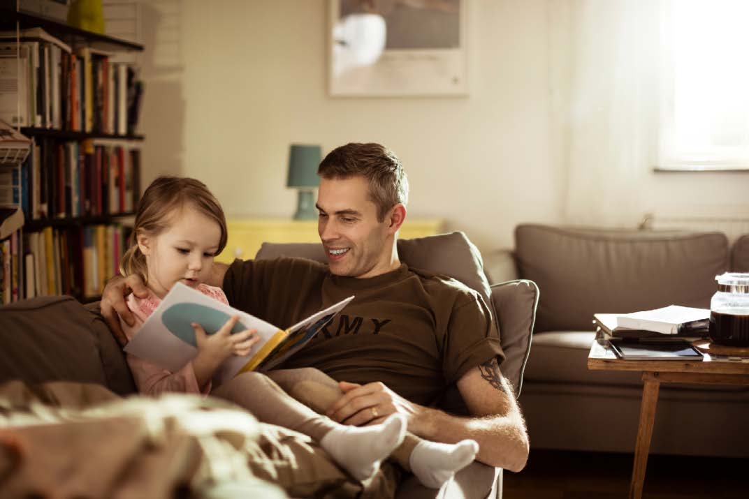 FATHER AND DAUGHTER SITTING ON COUCH AND READING